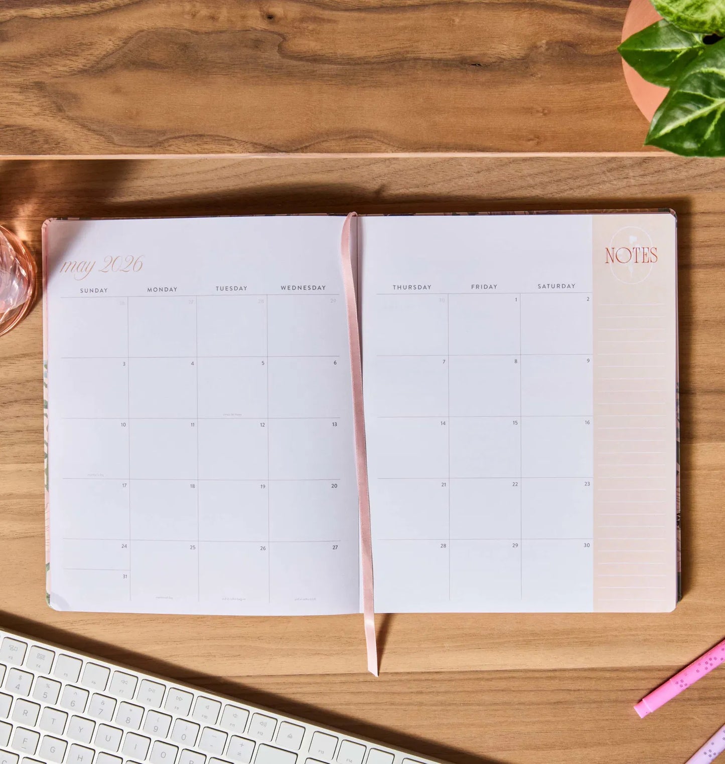 Open planner on a wooden desk with a keyboard and pen