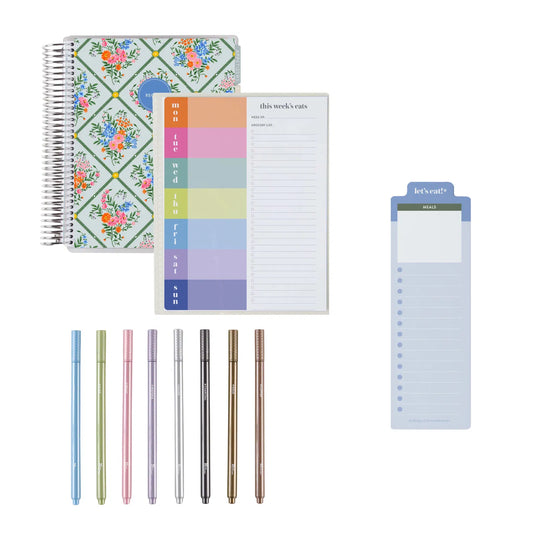 Assorted stationery items including a floral notebook, colorful sticky notes, and pens on a white background.