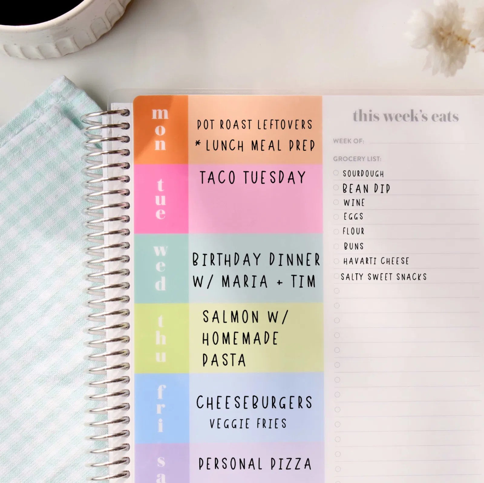 Weekly meal planner with colorful days of the week and text on a white surface.