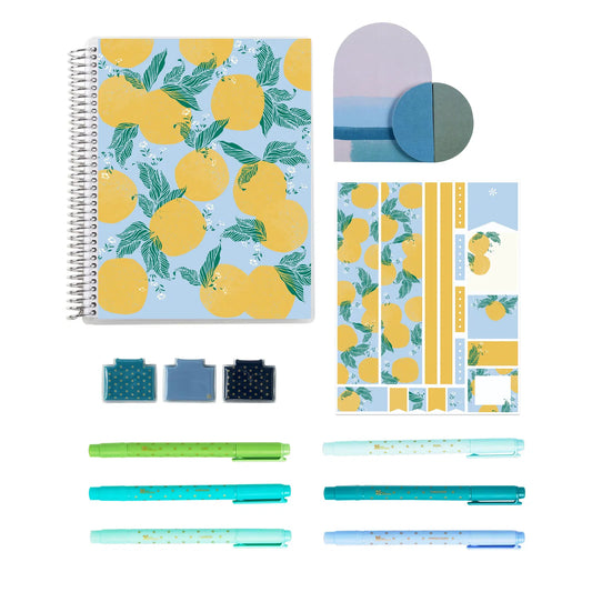 Stationery set with a notebook, pens, and other items featuring lemon patterns on a white background.