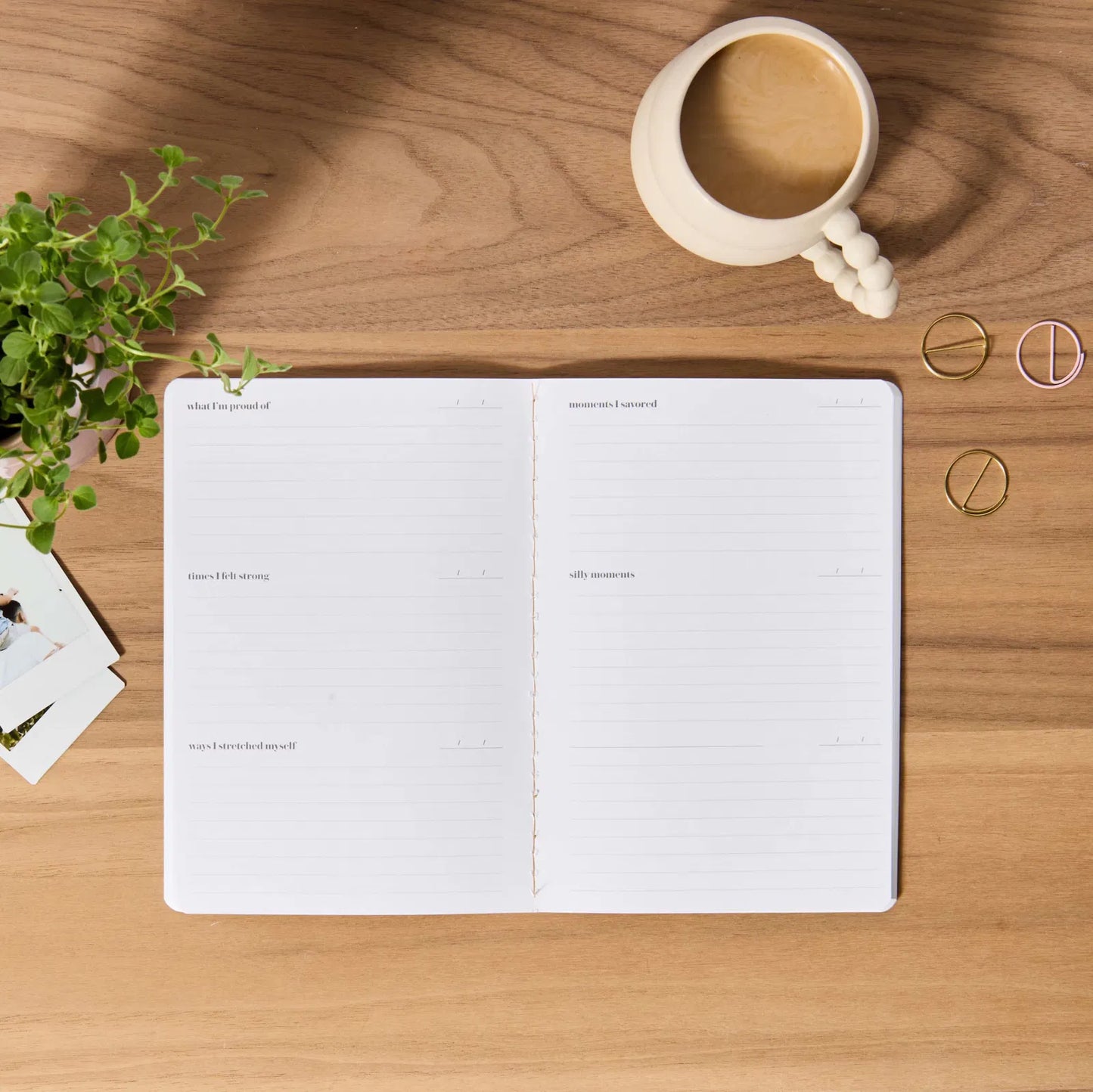 Open notebook on a wooden desk with a cup of coffee and decorative items.
