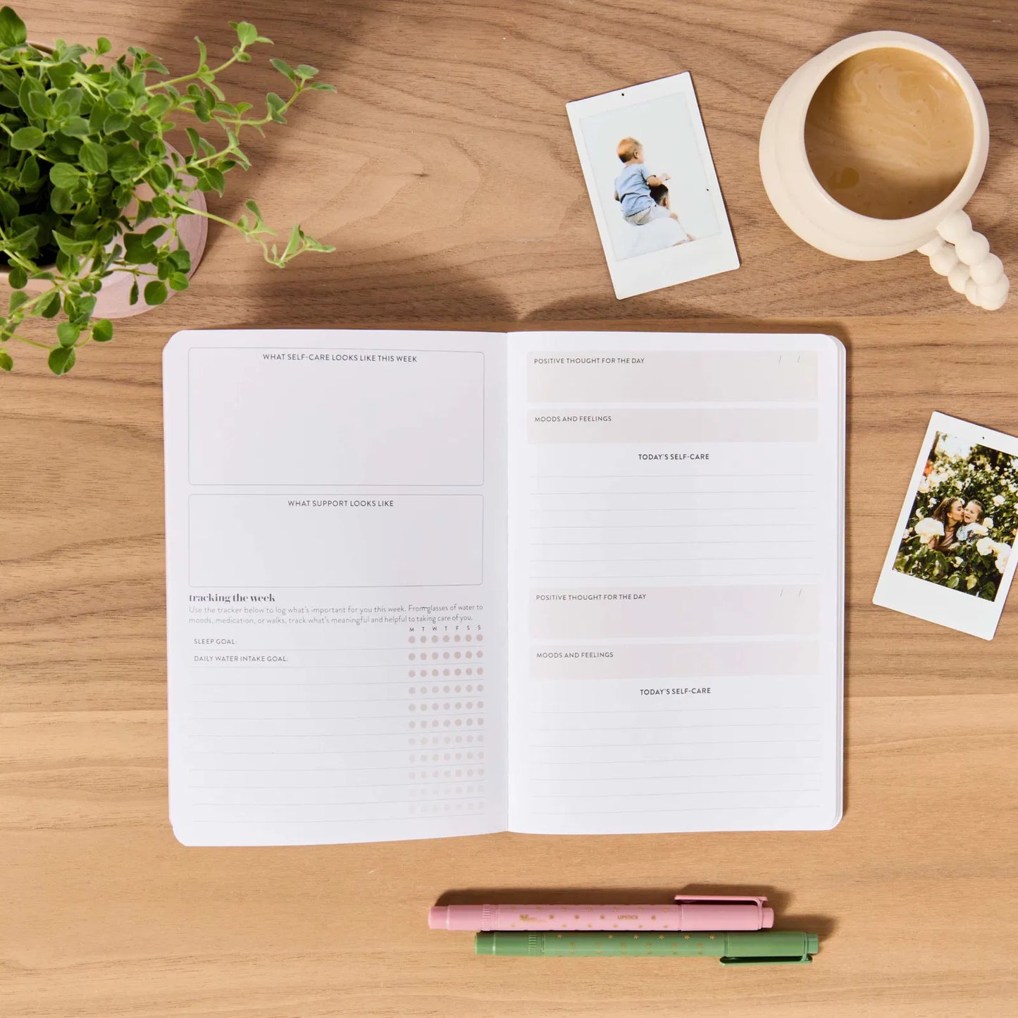 Open planner on a wooden desk with a coffee cup, photos, and pens.