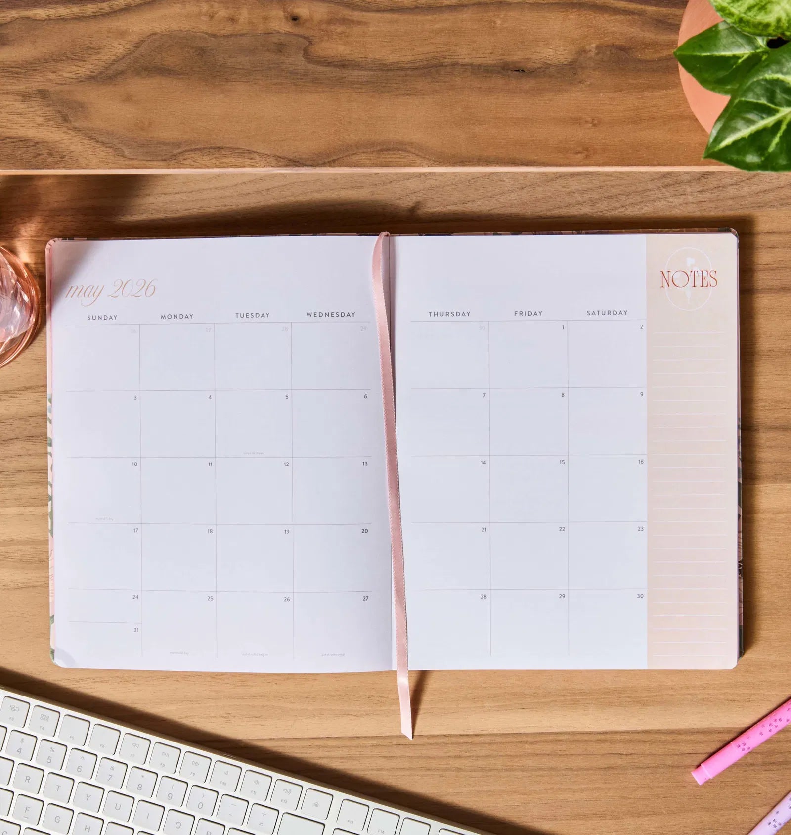 Open planner on a wooden desk with a keyboard and pen