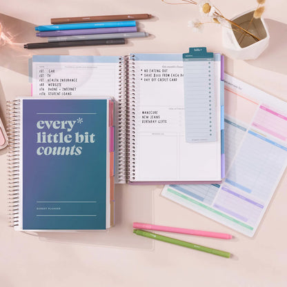 Open budget planner with colorful pens and sticky notes on a light surface